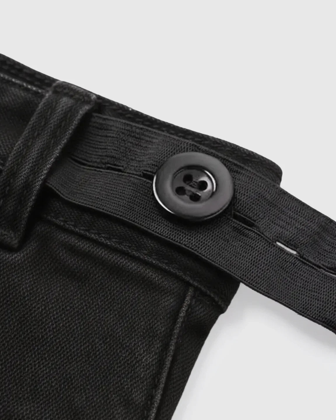 Close-up of black maternity jeans with adjustable elastic waistband and button closure.