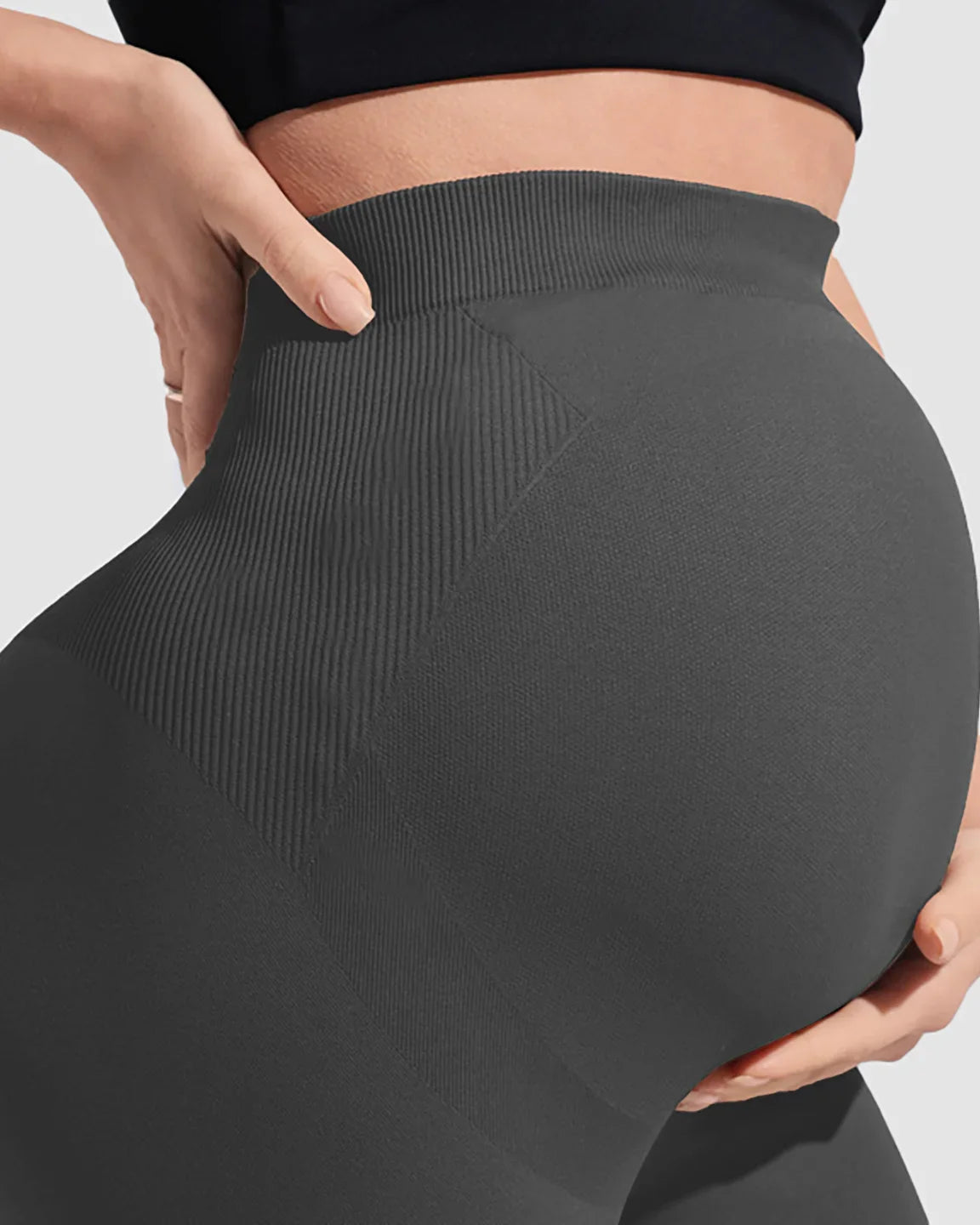 Dark grey over-belly bootcut maternity pants with ribbed waistband and seamless design, supporting a pregnant belly.