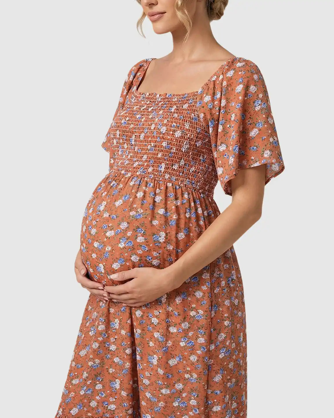 Maternity midi dress in rust with blue floral print, smocked bodice, flutter sleeves, and tiered skirt.