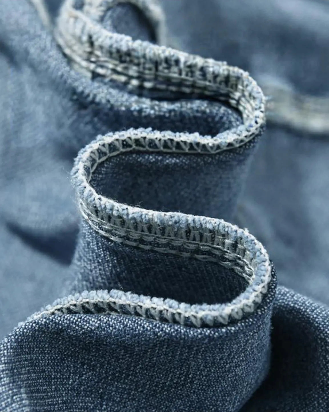 Close-up of blue denim fabric with a serged seam, highlighting the soft, stretchy material of maternity cargo jeans.