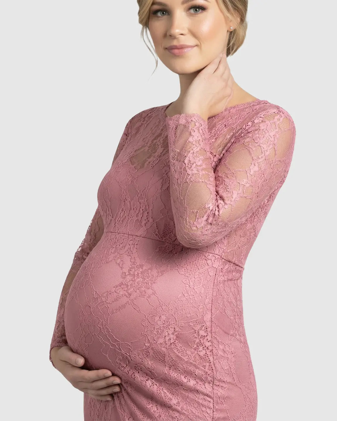 Pregnant woman in a pink sheer lace trumpet maternity gown with long sleeves and a classic neckline.