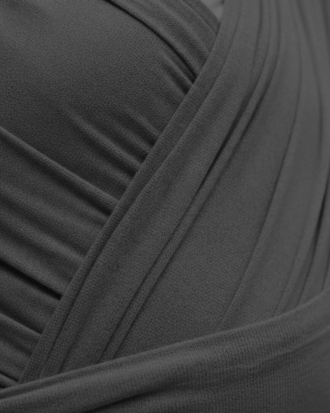 Close-up of a dark gray, soft, breathable fabric baby wrap carrier with adjustable, ruched details.