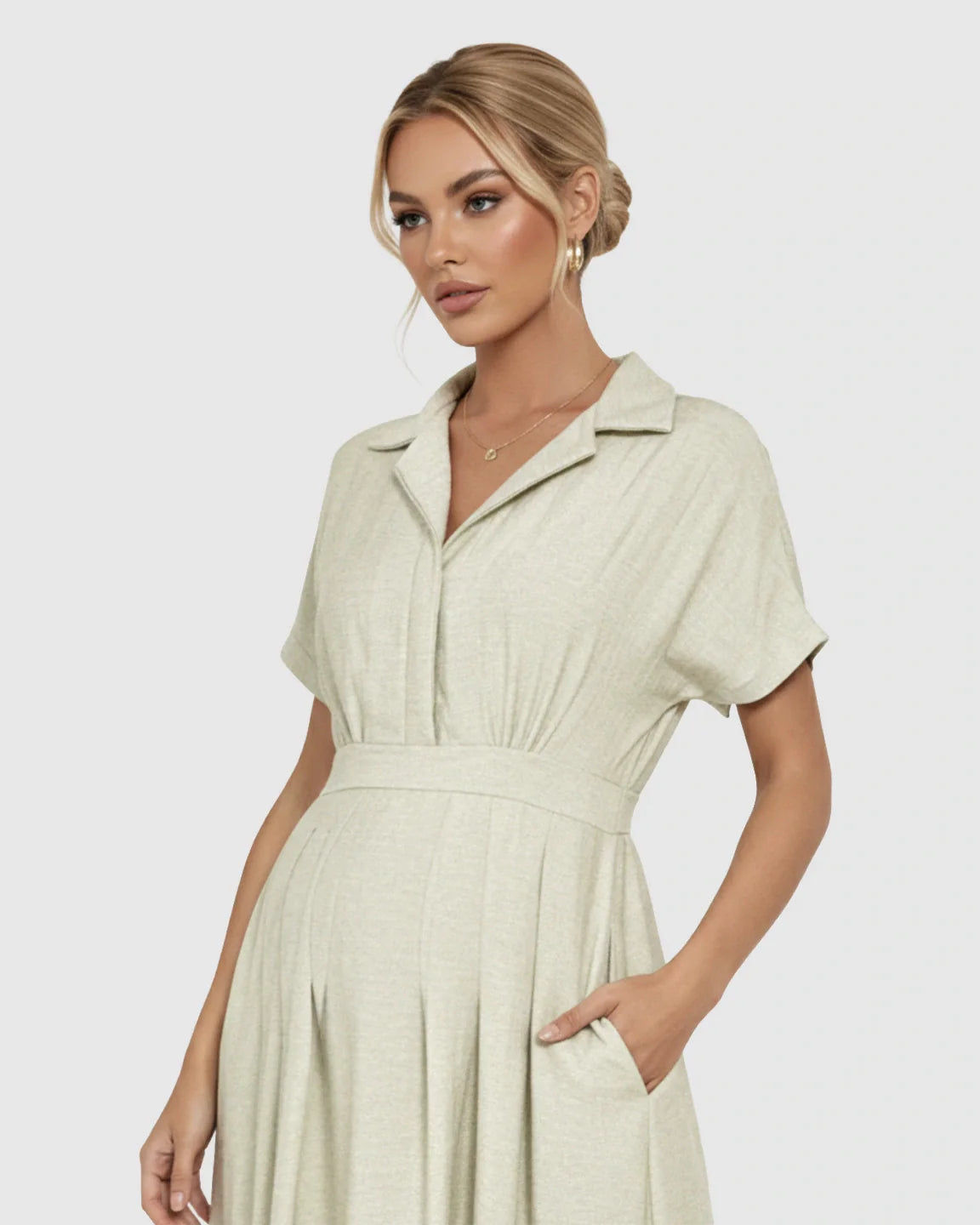 Blonde woman in a light green, lapel collar A-line maternity midi dress with short sleeves and pockets.