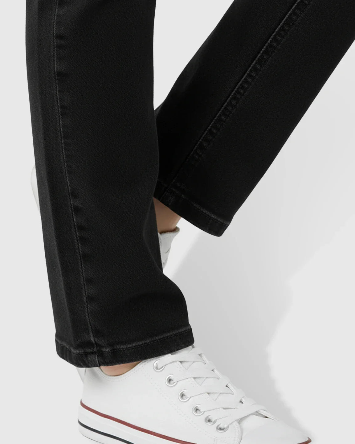 Black straight-leg maternity jeans with white sneakers, showcasing the denim texture and relaxed fit.