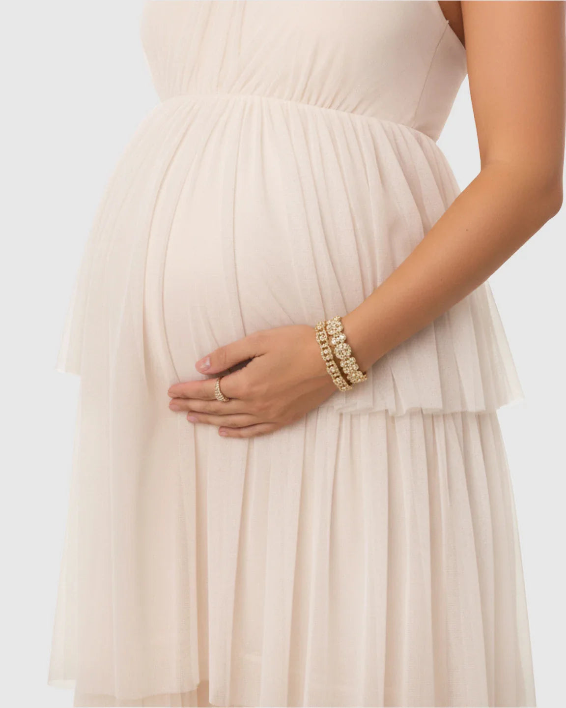 Maternity gown in light pink mesh with a tiered skirt and pleated bodice, flattering a pregnant belly.