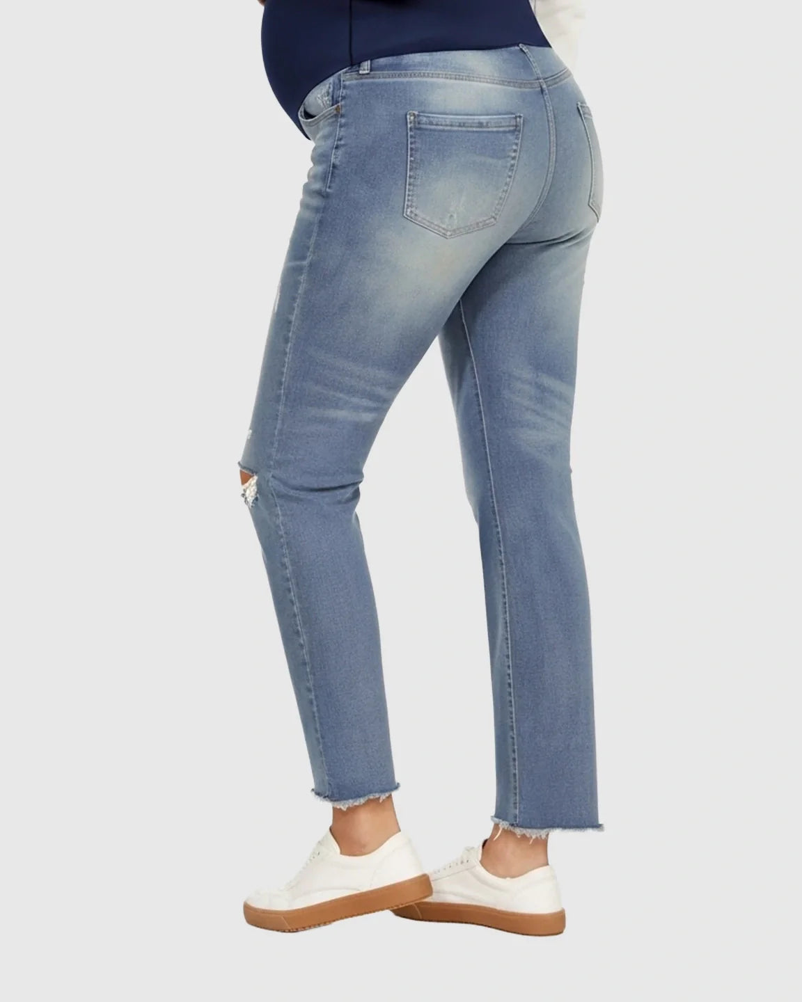 Light wash distressed maternity jeans with a high belly band, frayed hem, and ripped knee.