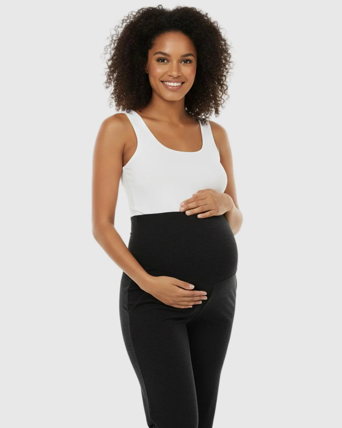 Smiling pregnant woman in a white tank top and black foldable waistband wide-leg maternity lounge pants.