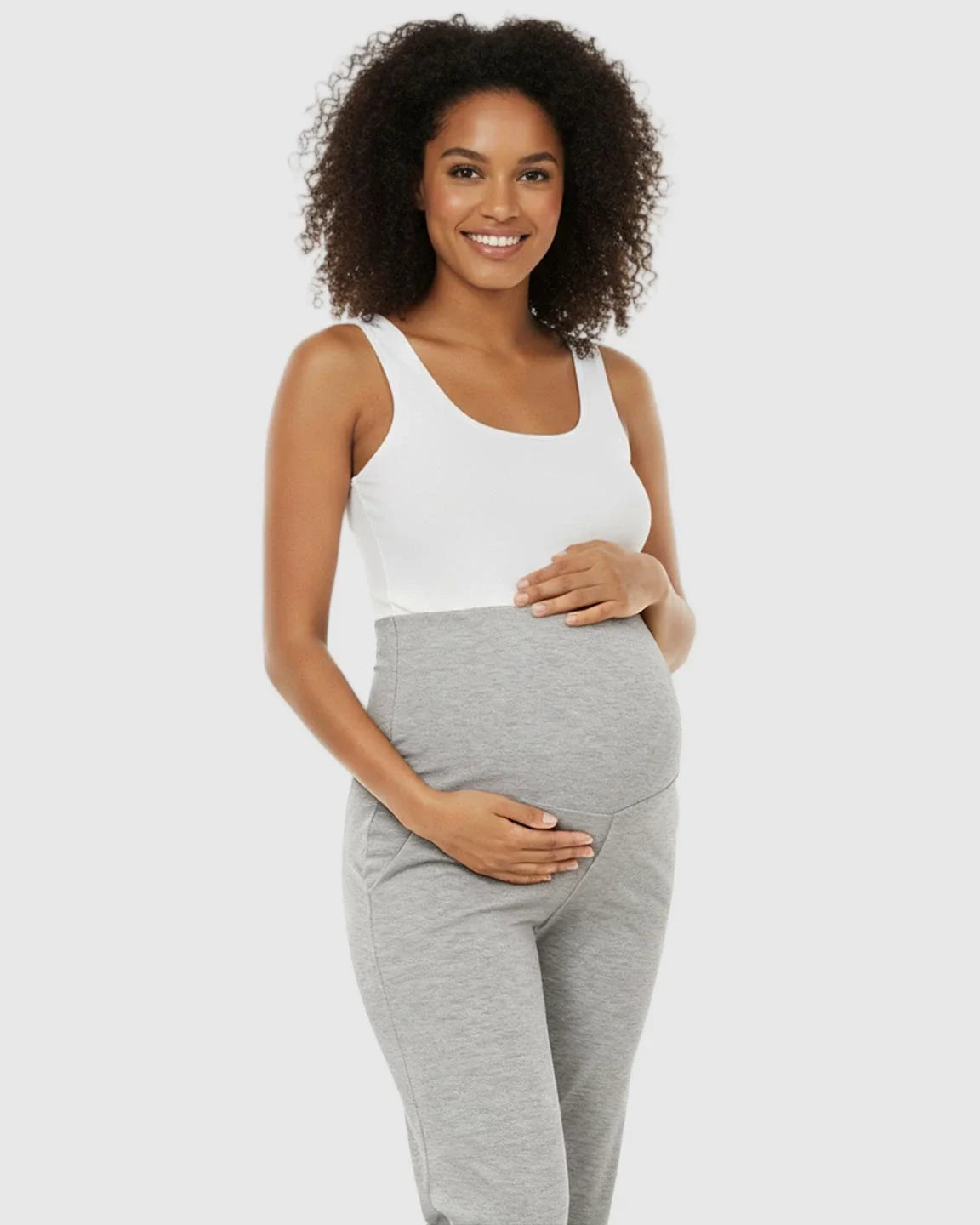 Smiling pregnant woman in a white tank top and gray wide-leg maternity lounge pants with a foldable waistband.
