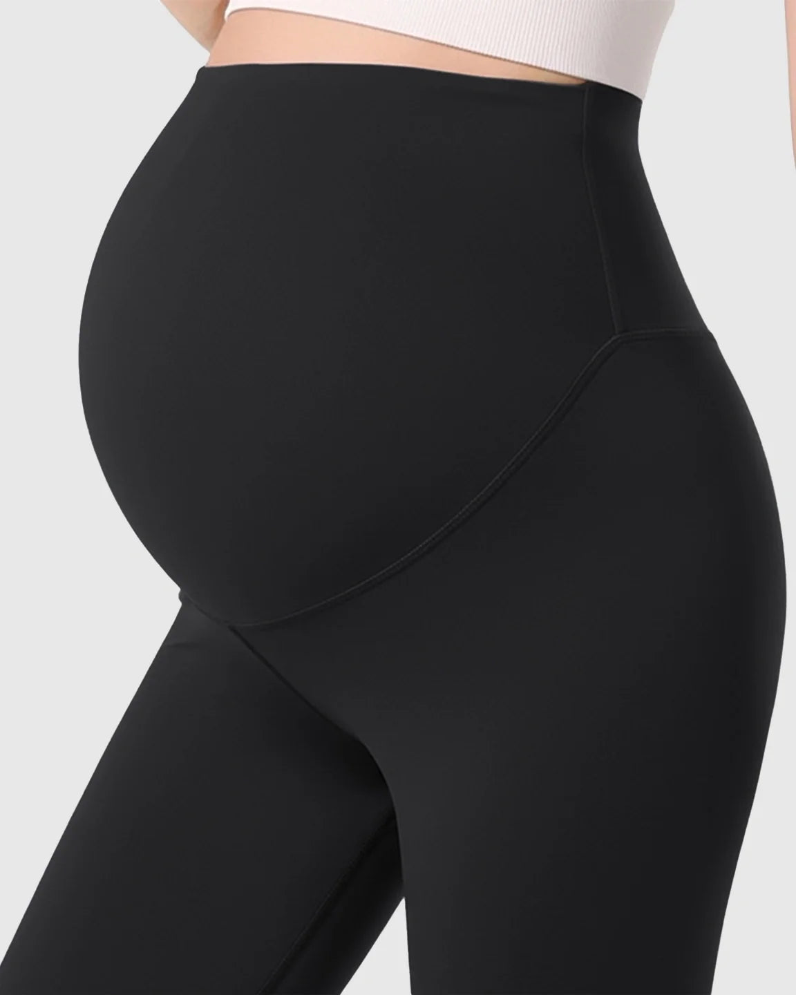 Black double-layer belly support maternity leggings, ultra-stretch fabric, cradling a pregnant bump.