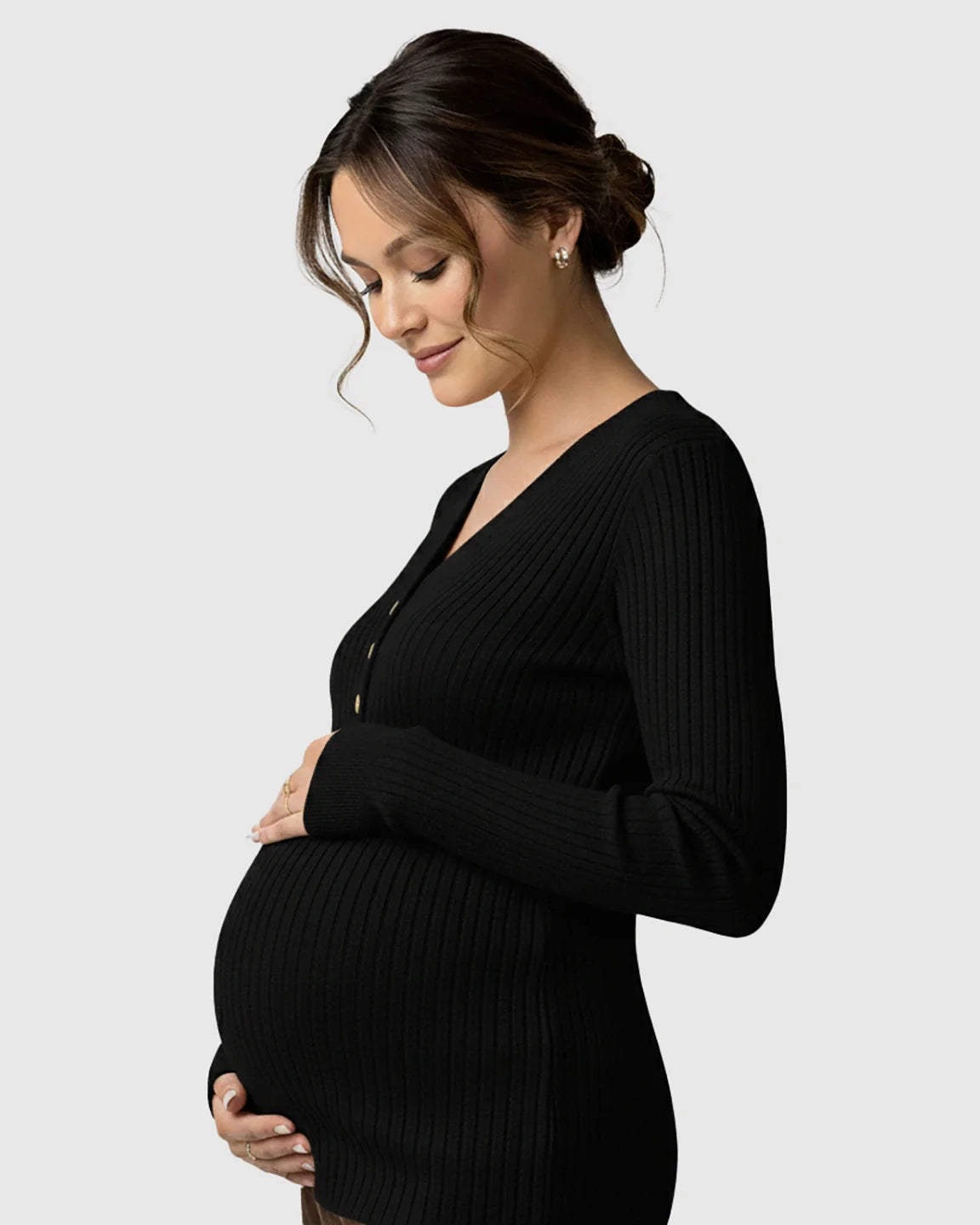 Pregnant woman in black ribbed V-neck maternity nursing sweater with gold buttons, cradling her belly.