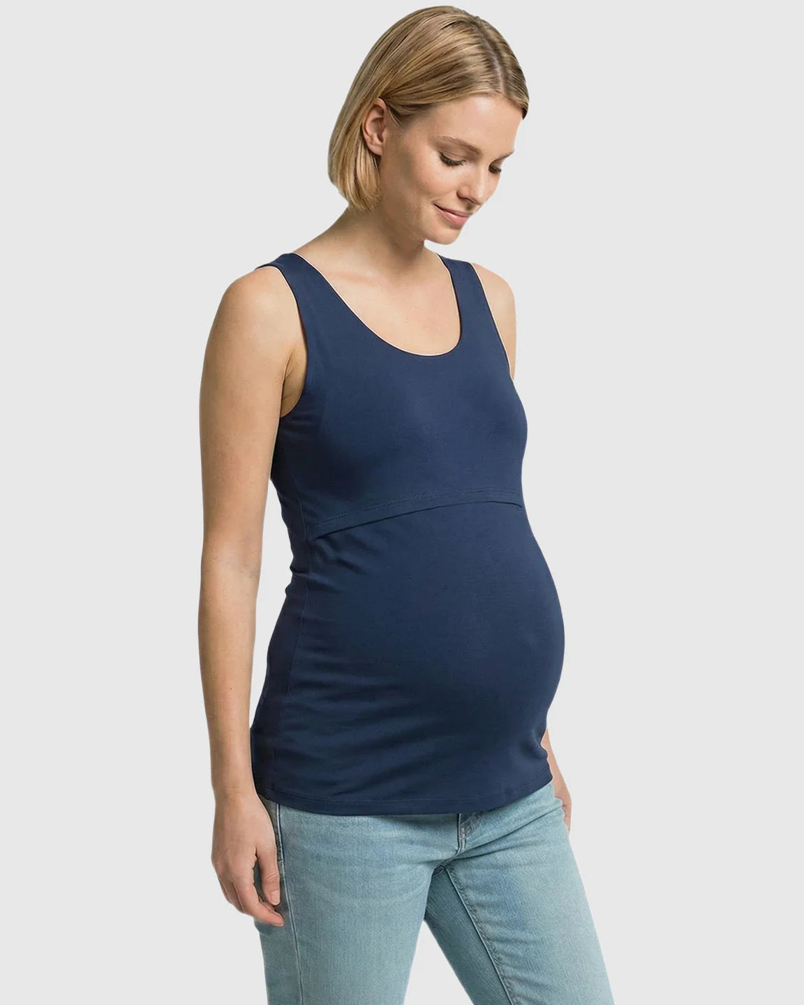 Pregnant woman in a navy blue stretch nursing-access maternity tank top and light wash jeans.