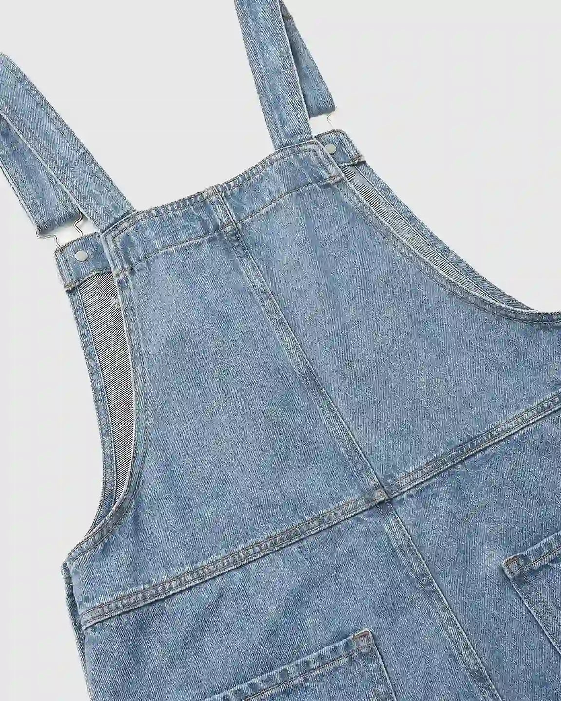 Light blue denim maternity jumpsuit with adjustable straps and loose fit.