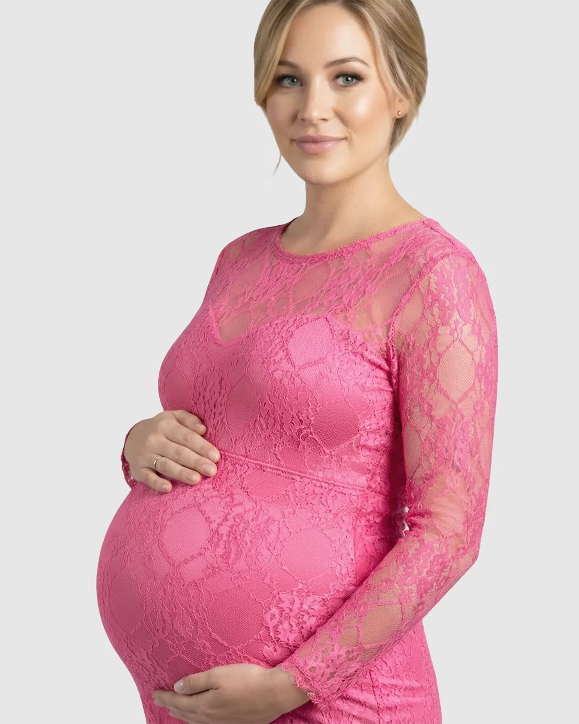 Pregnant woman in a pink sheer lace trumpet maternity photoshoot gown with long sleeves.