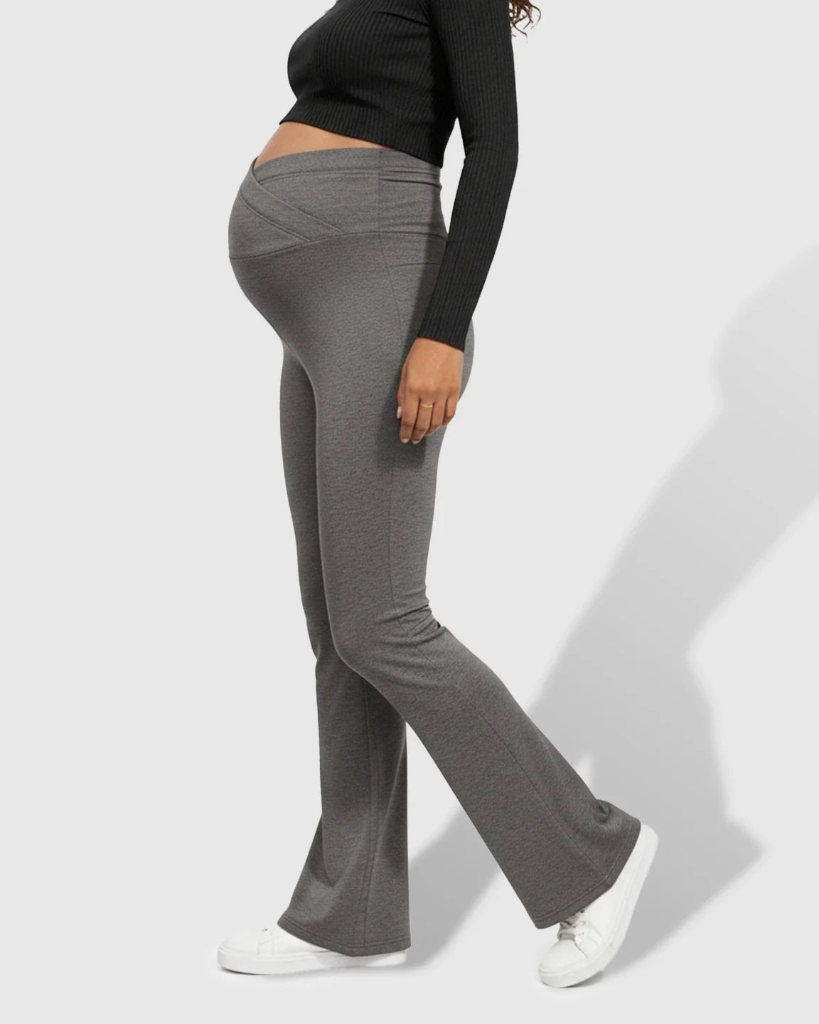 Maternity model wearing gray crossed waistband flared pants, showcasing the supportive belly band and comfortable fit.