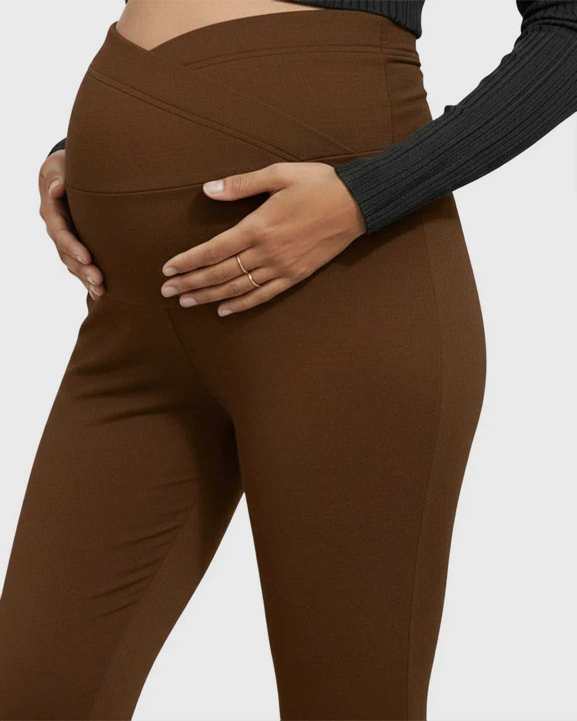 Brown flared maternity pants with a crossed waistband, gently hugging a pregnant belly.
