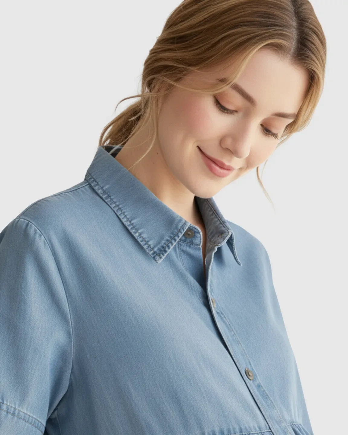 Blonde woman in a light blue tiered denim maternity midi dress with a button-front shirt style.