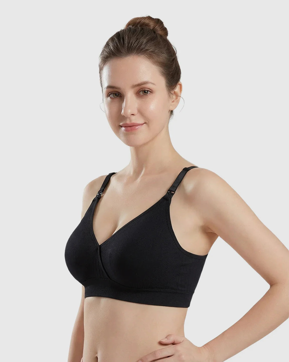 Woman wearing a black seamless cross-front wireless nursing bra with adjustable straps.