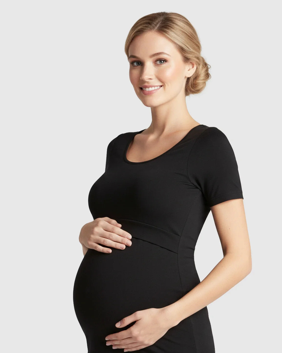 Smiling pregnant woman in a black stretch-fit scoop-neck nursing t-shirt, cradling her baby bump.