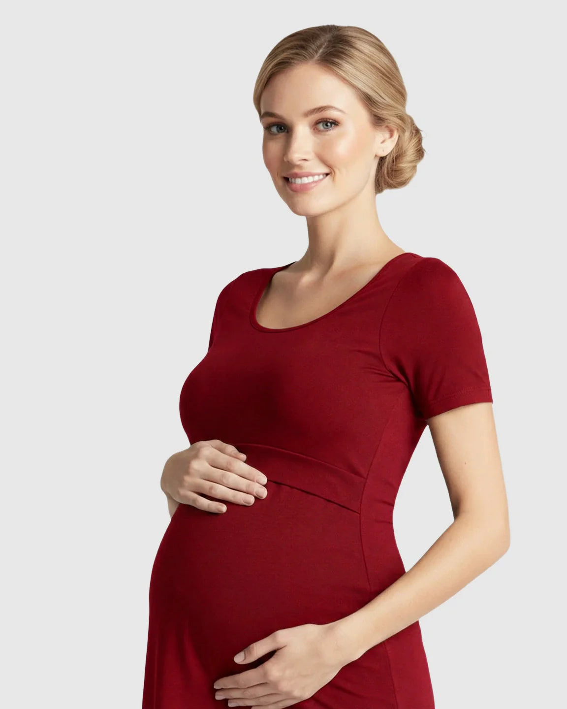 Smiling pregnant woman in a red stretch-fit scoop-neck nursing t-shirt, cradling her belly.