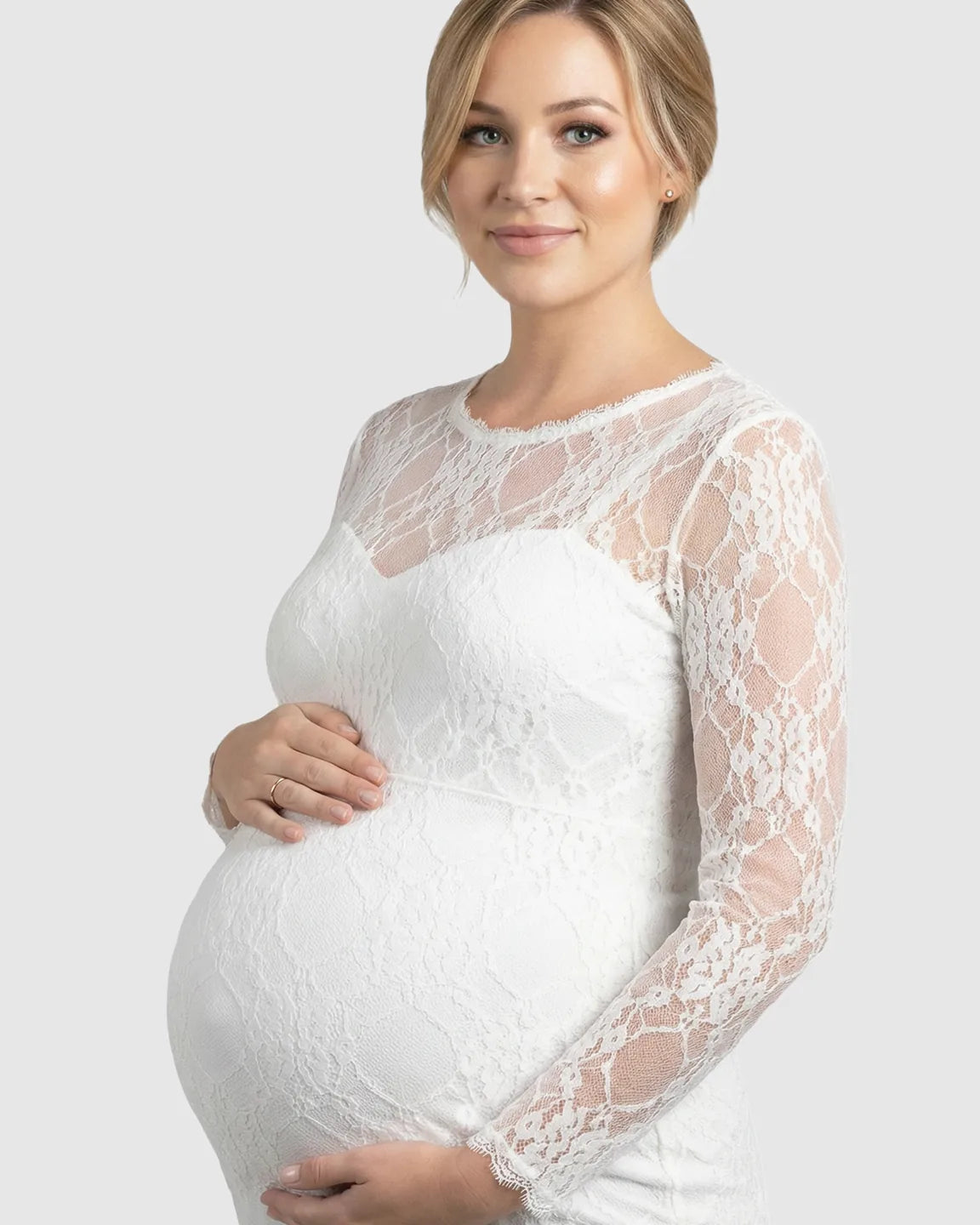 Pregnant woman in a white sheer lace trumpet maternity gown with long sleeves and a classic neckline.