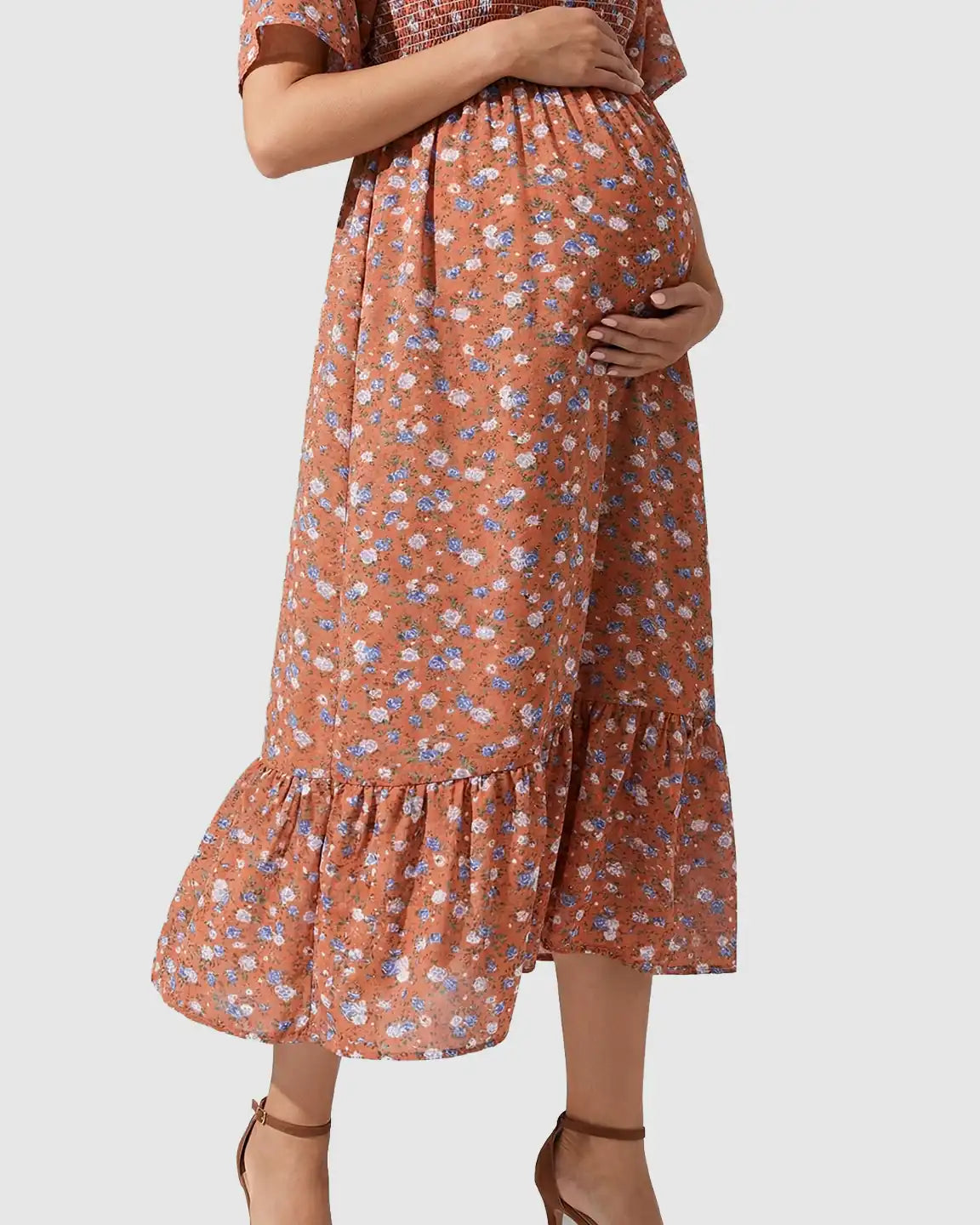 Maternity midi dress in rust with blue floral print, flutter sleeves, smocked top, and tiered skirt.