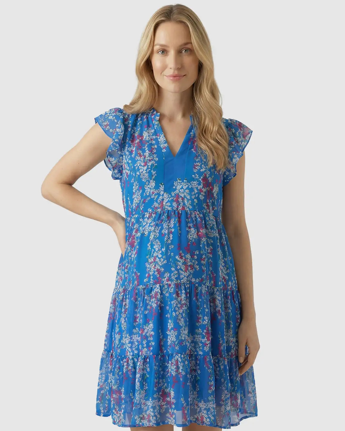 Blonde woman in a blue floral chiffon V-neck A-line maternity dress with flutter sleeves.
