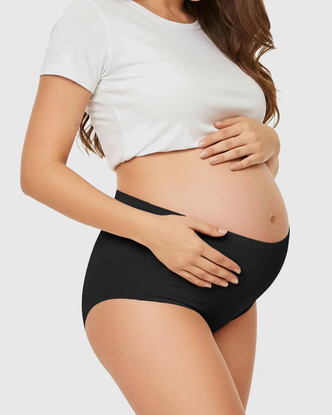 Pregnant woman wearing black seamless high-waist support maternity underwear, gently cradling her belly.
