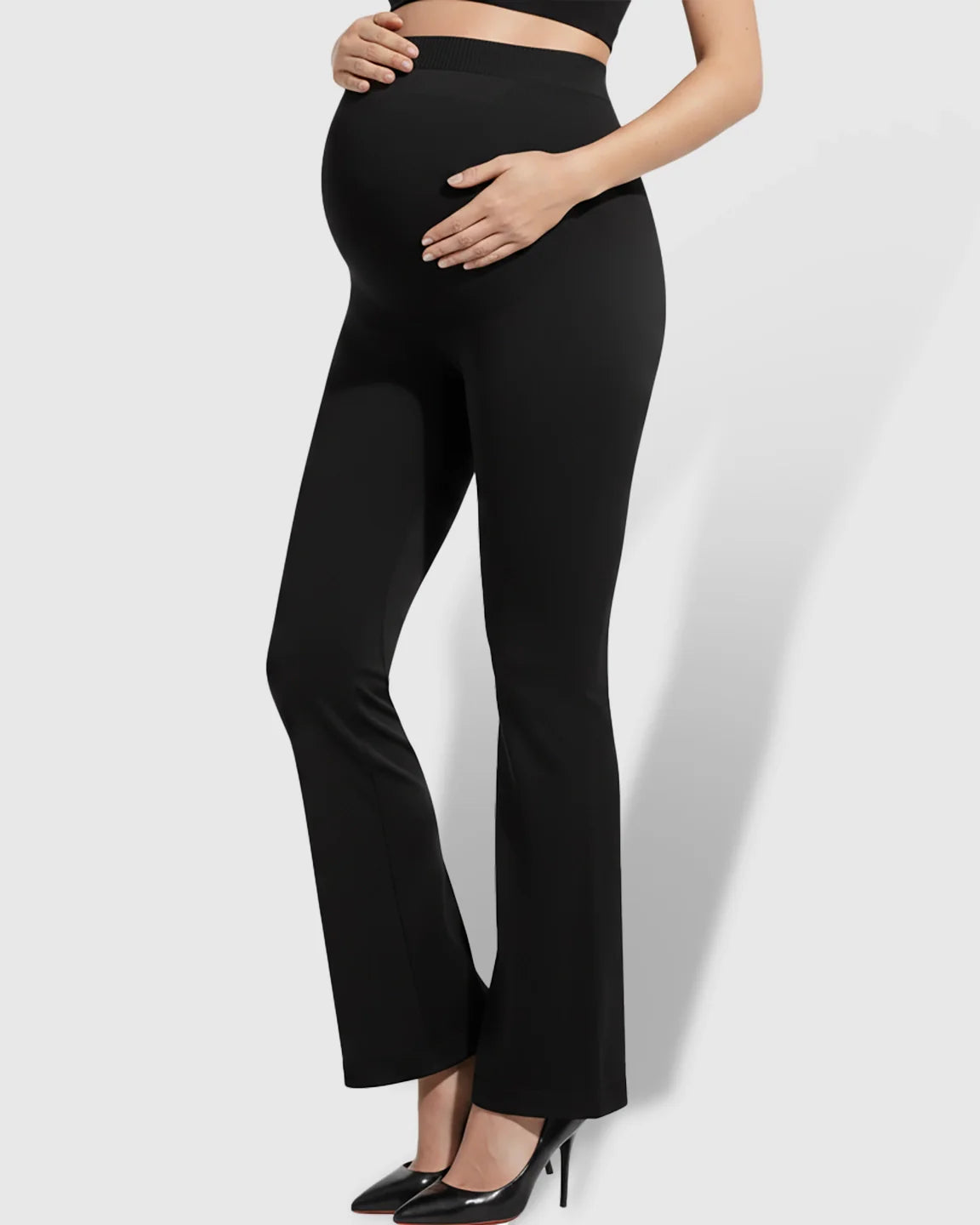 Maternity model wearing black over-belly bootcut pants with a soft flare and supportive waistband.