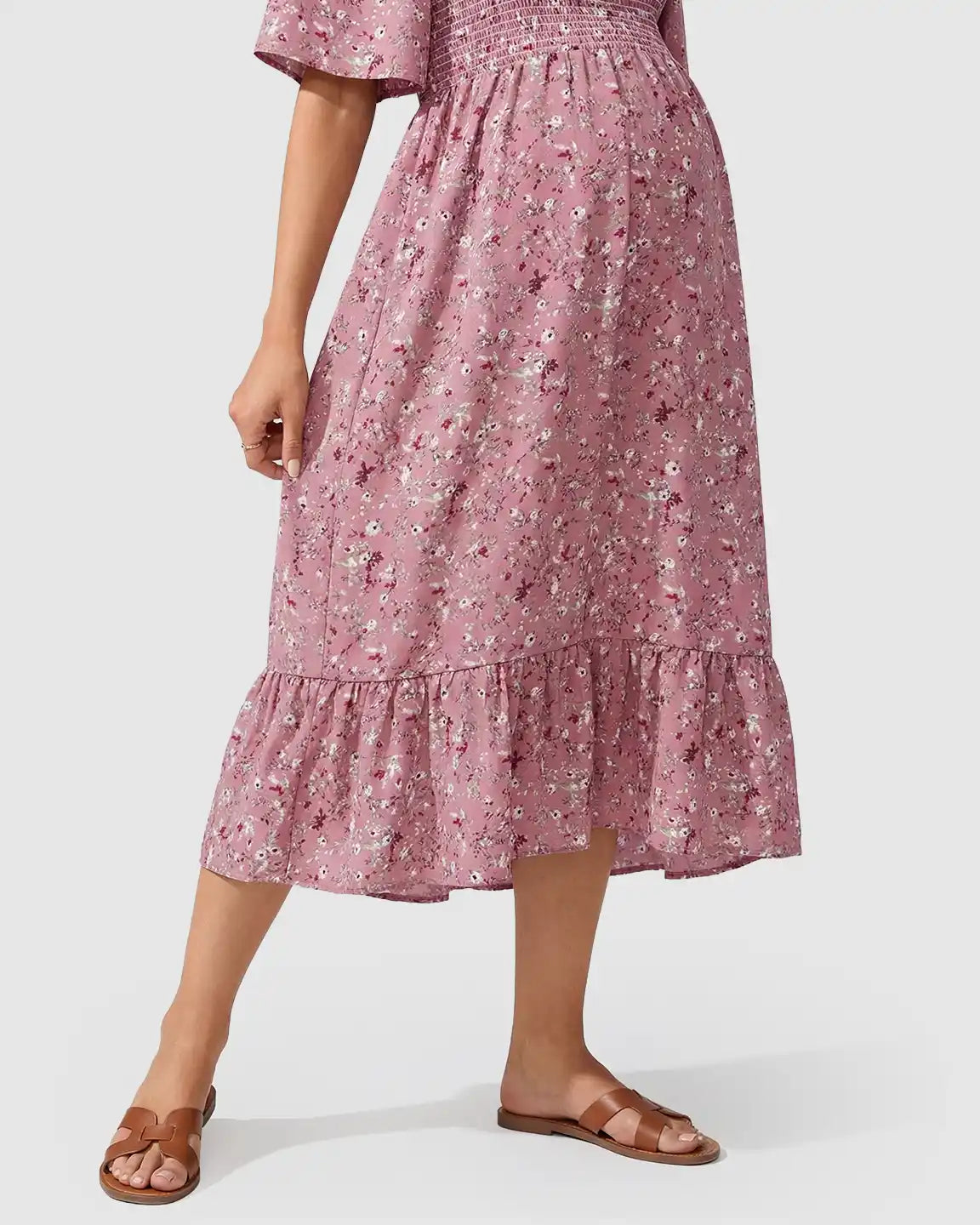 Pink floral flutter-sleeve smocked maternity midi dress with tiered skirt and brown sandals.