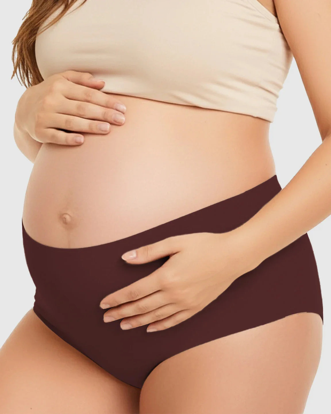 Pregnant woman wearing seamless, high-waist, dark brown maternity support underwear.