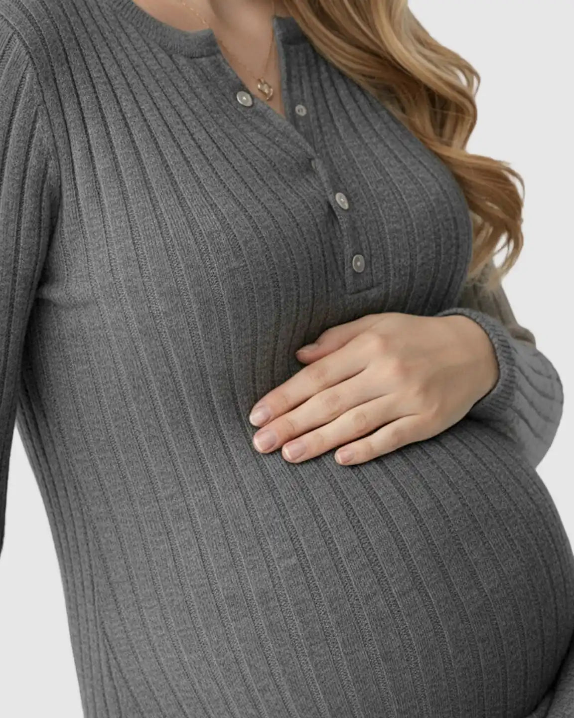 Pregnant woman in a charcoal ribbed knit A-line maternity maxi dress with long sleeves and button henley neckline.