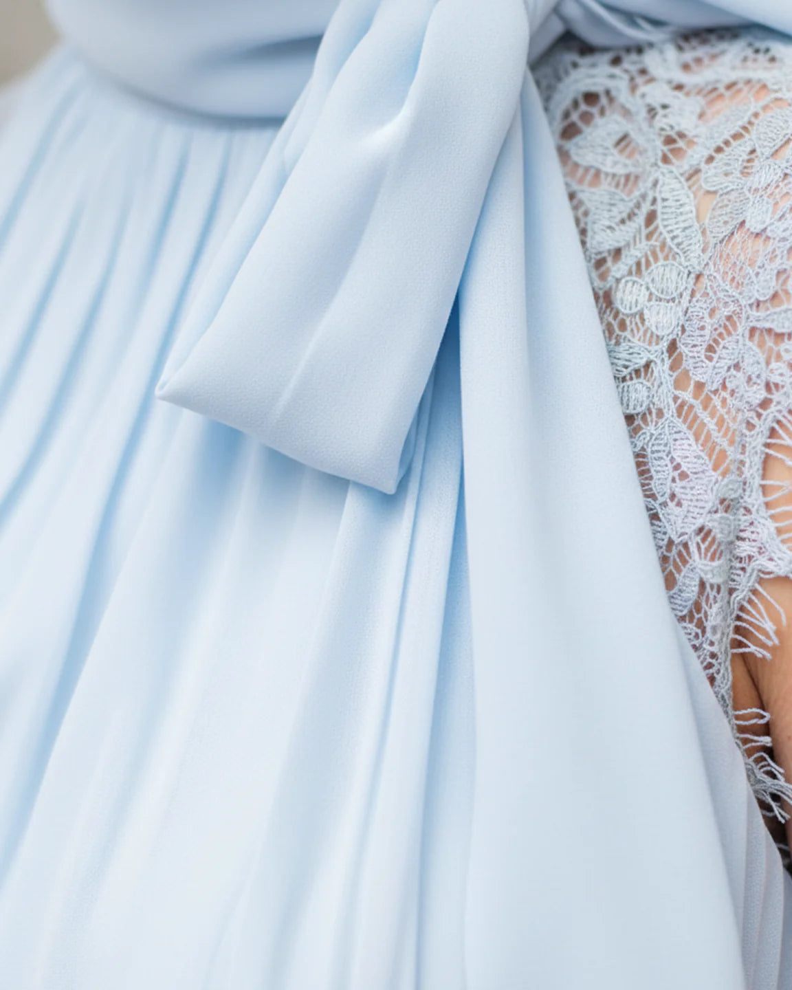 Light blue chiffon maternity midi dress with high-neck tie detail and delicate lace sleeves.