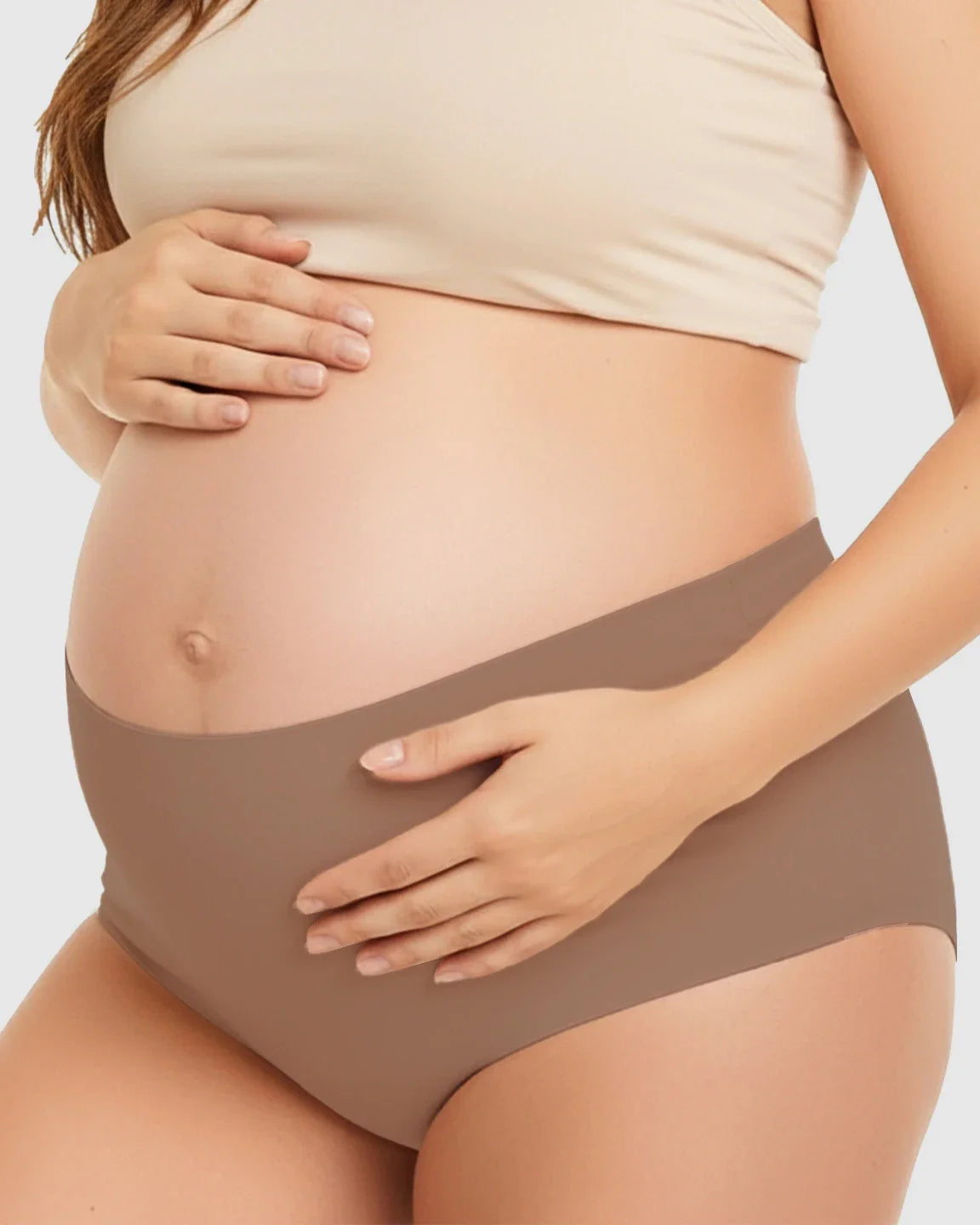 Pregnant woman wearing seamless, high-waist, mocha-colored maternity support underwear.