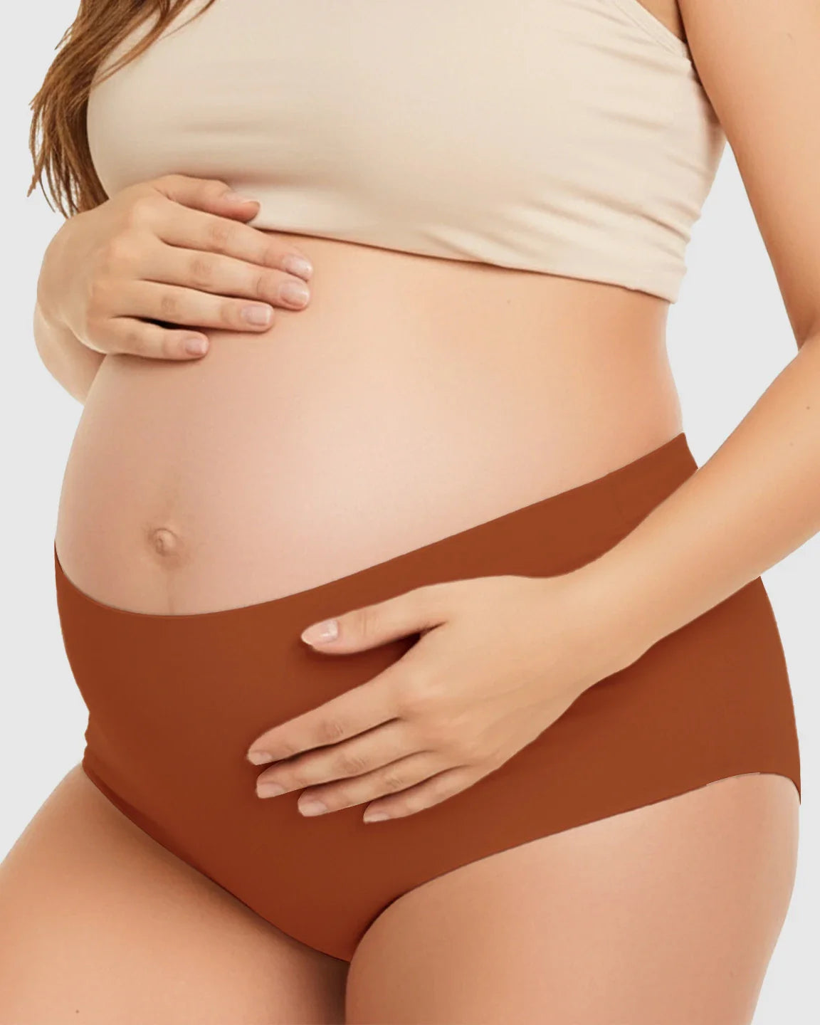 Pregnant woman wearing seamless high-waist rust-colored maternity support underwear.