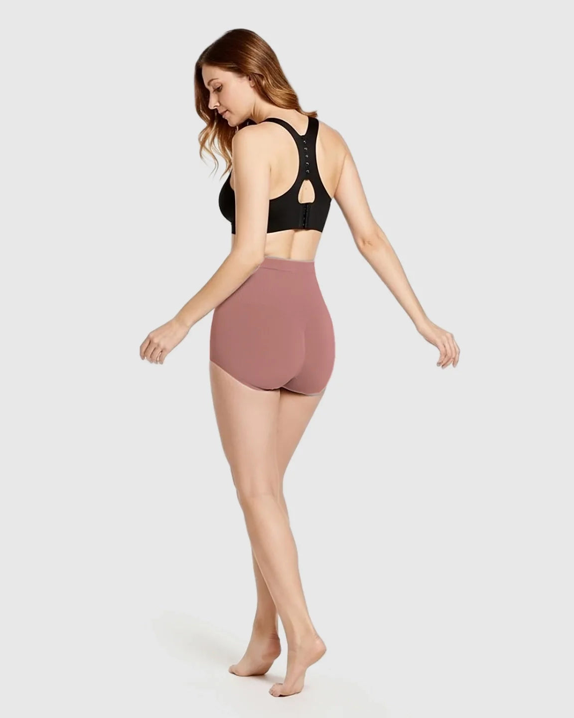 Woman modeling rose-colored, seamless, high-waist maternity panties, designed for comfort and support.