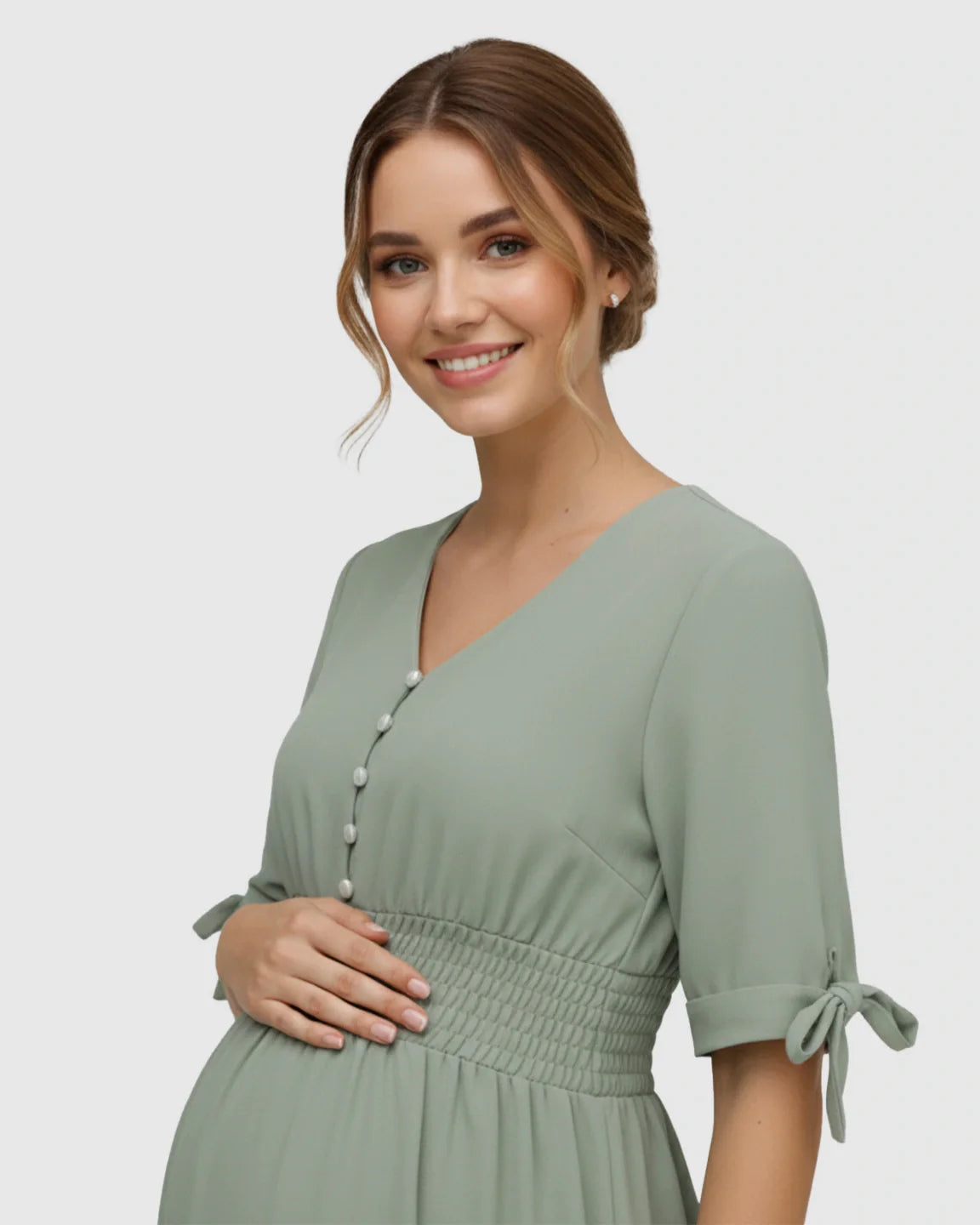Smiling pregnant woman in a mint green V-neck empire waist maternity maxi dress with pearl buttons and tied sleeves.