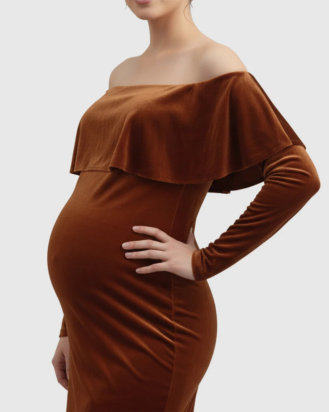 Velvet-touch elegant fitted maternity photoshoot gown in rust brown, off-shoulder with ruffle detail, long sleeves.