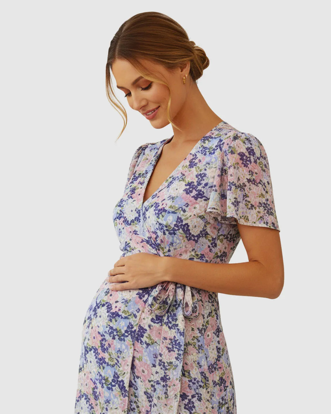 Maternity V-neck wrap-style midi dress with flutter sleeves, adjustable tie waist, and a breezy floral print.