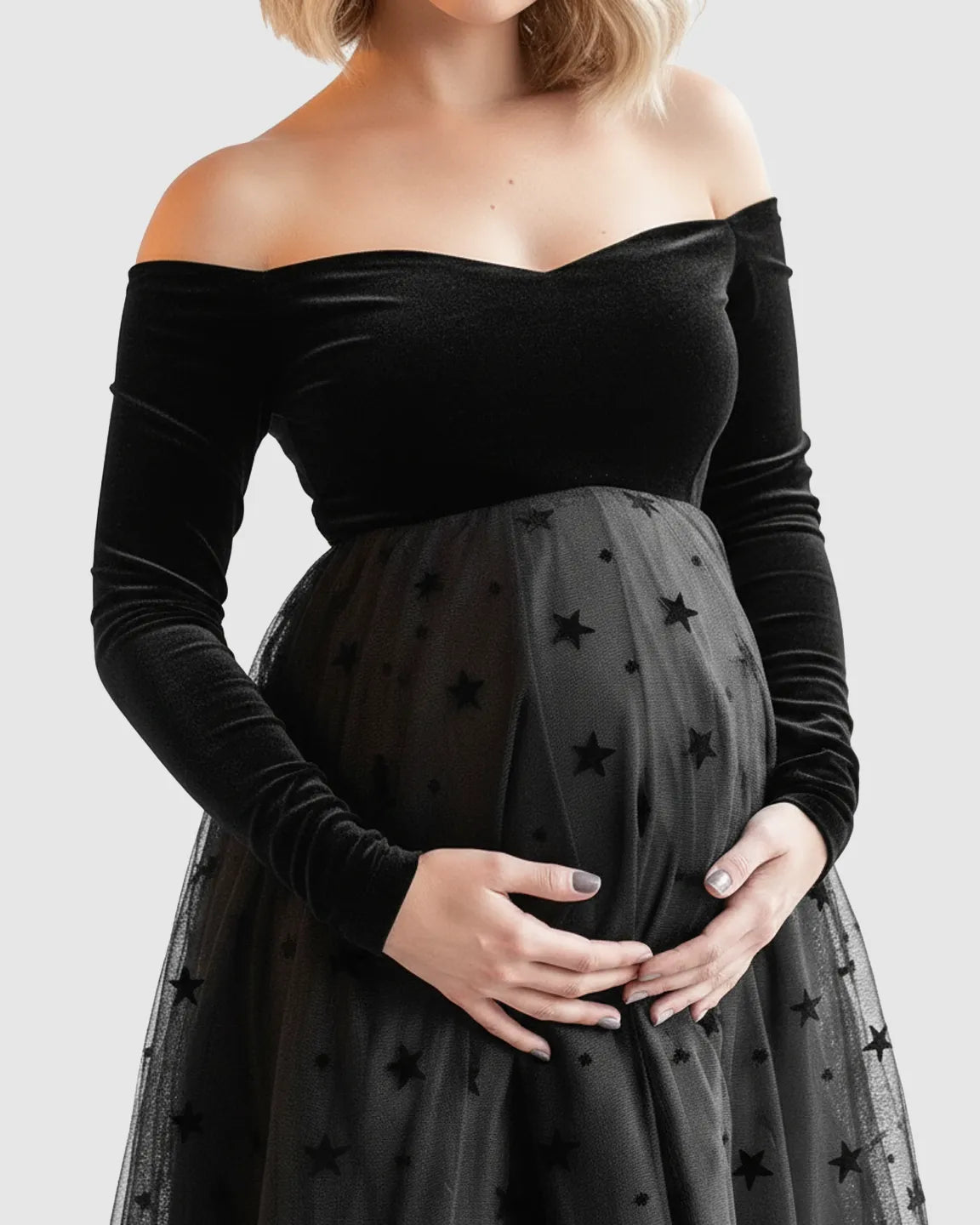 Black velvet off-shoulder maternity midi dress with a star-flocked mesh skirt.