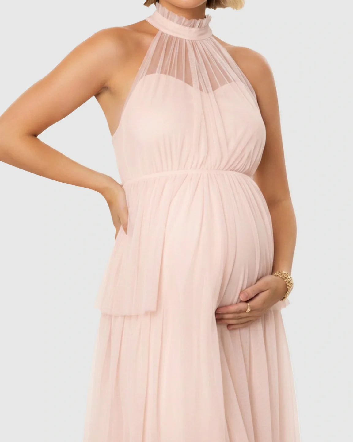 Maternity model in a pink halter-neck tiered mesh gown, highlighting the bump.