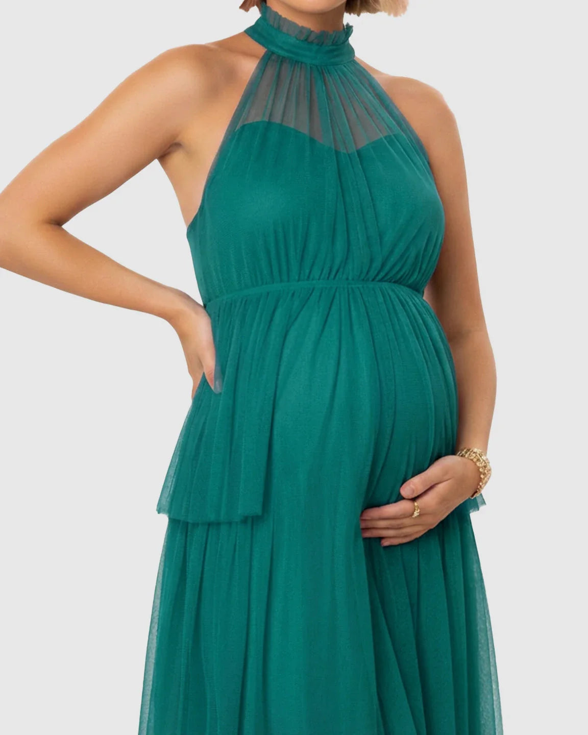 Emerald green halter neck tiered mesh maternity gown, flattering the bump with a flowing skirt.