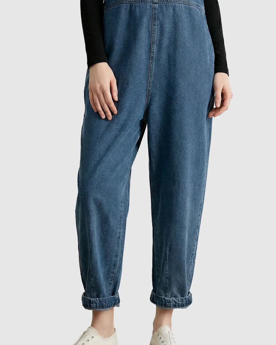 Loose-fit blue denim maternity overalls with a relaxed waistband and cuffed ankles, worn over a black long-sleeve top.