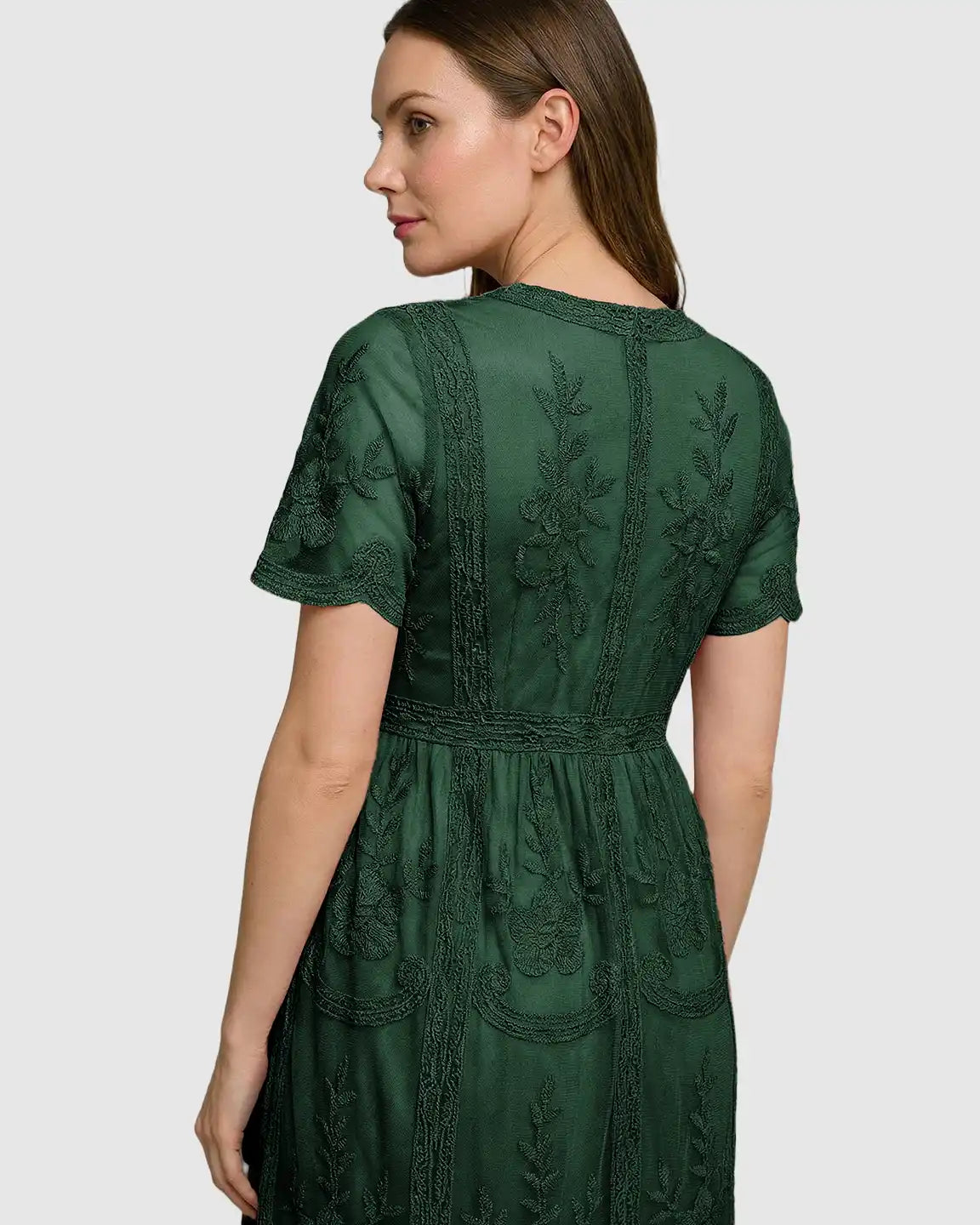 Woman in a dark green lace maternity midi dress with short sleeves and intricate floral embroidery.