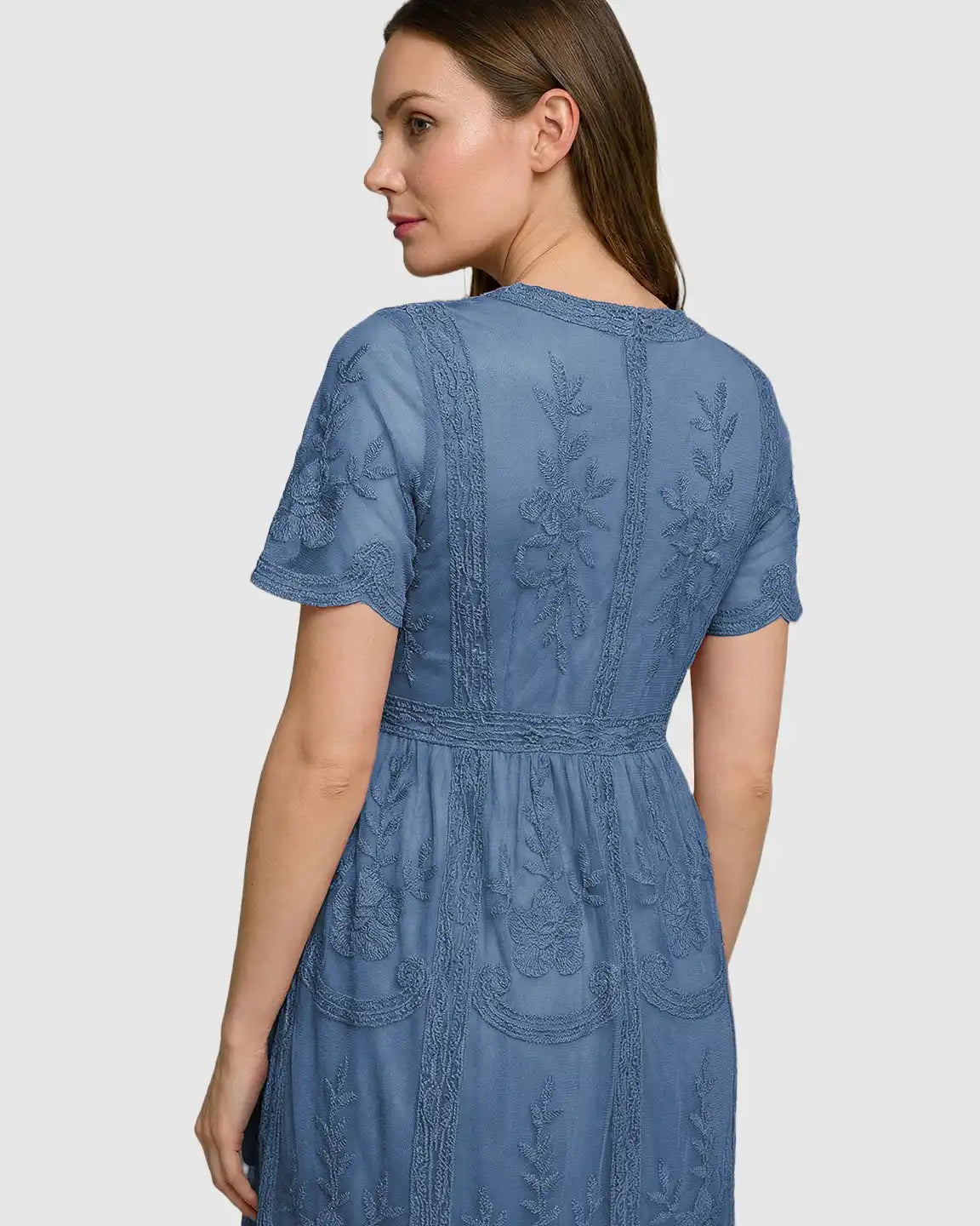 Woman in a blue lace maternity midi dress with short sleeves and intricate floral embroidery.