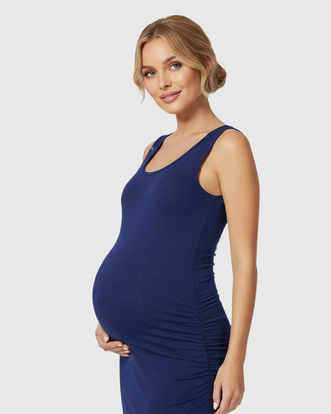 Pregnant woman in a navy sleeveless bodycon maternity dress with side ruching, showcasing a comfortable, fitted style.