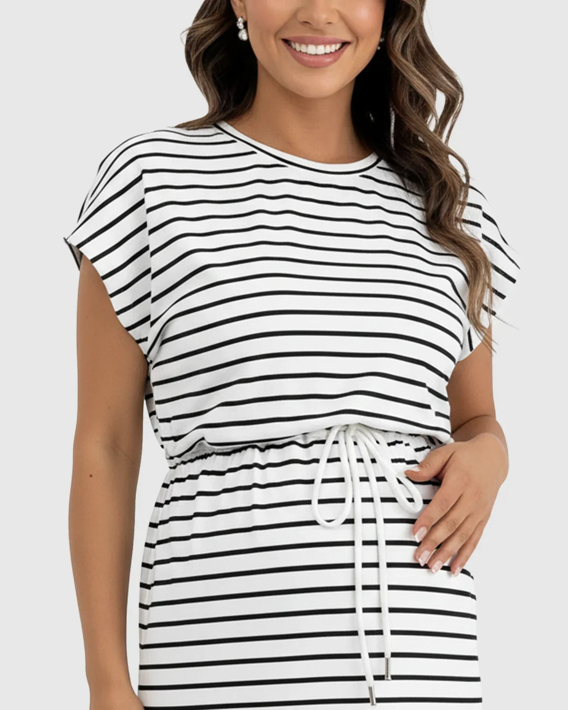 Smiling woman in a black and white striped maternity midi dress with cap sleeves and adjustable drawstring waist.
