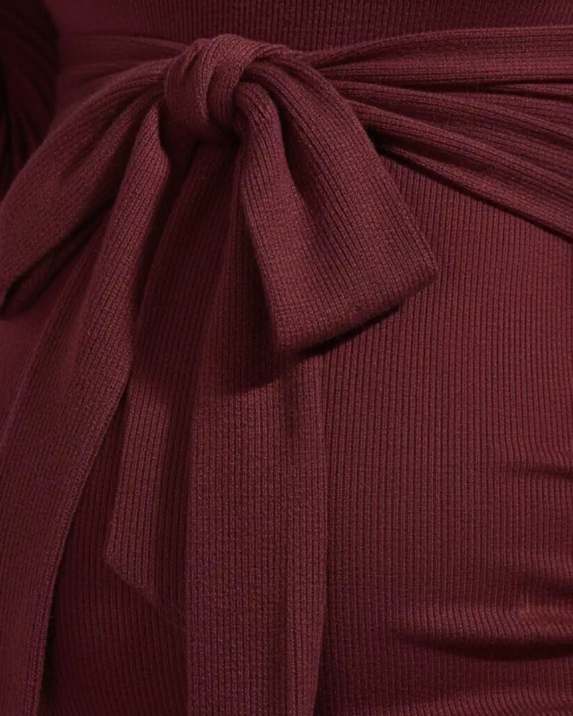 Close-up of a burgundy ribbed knit maternity dress with a tied waist bow.