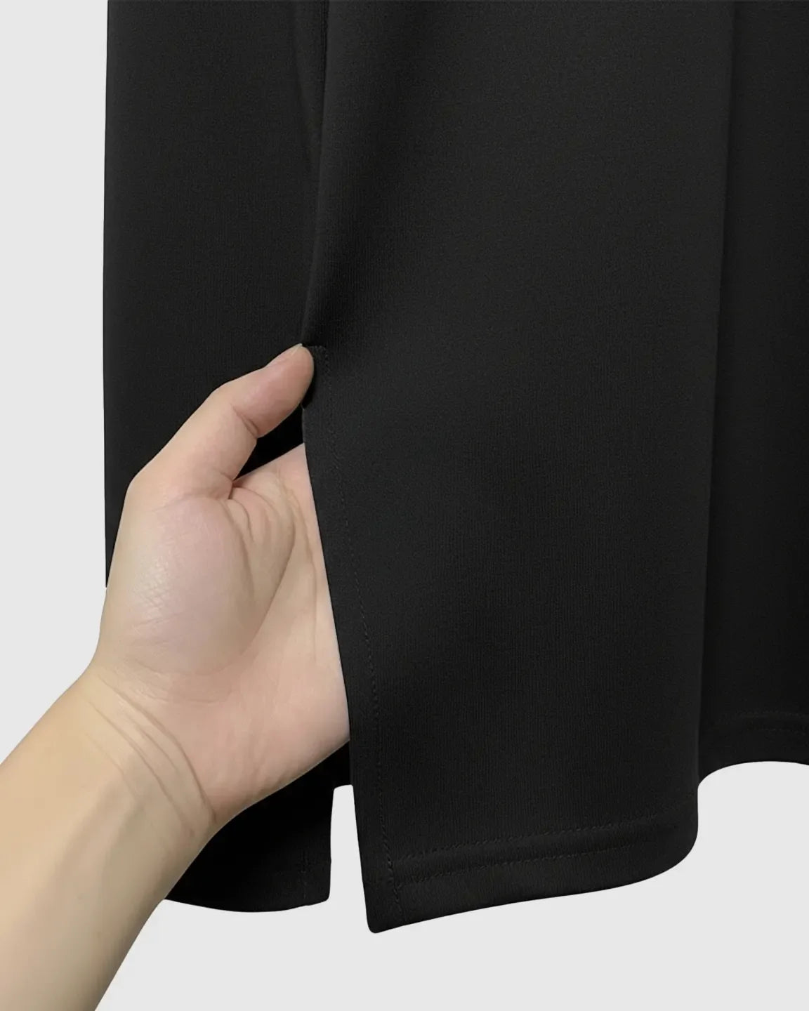 Hand pulling open a side slit on a black soft cotton maternity top.