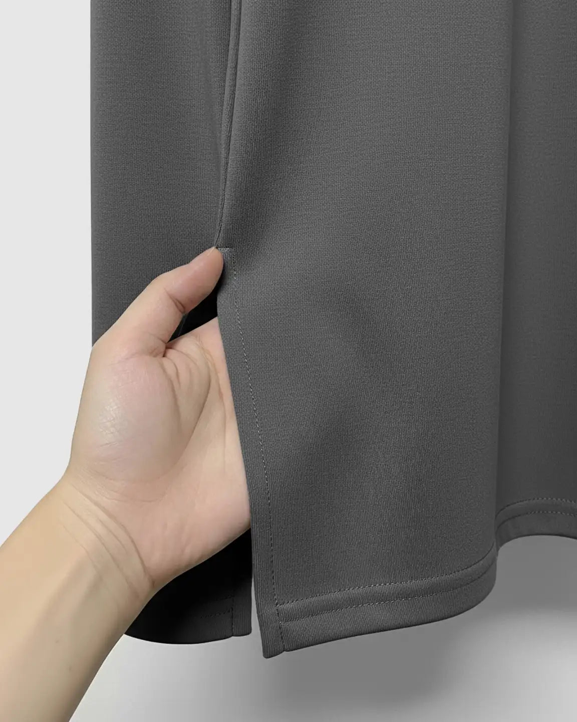 Hand pulling open the side slit of a dark gray, soft cotton maternity top.