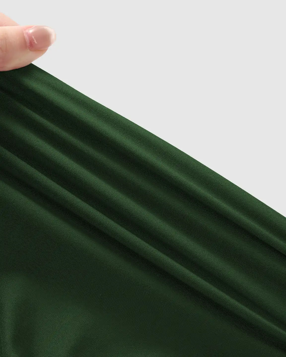 Hand stretching dark green, soft, supportive maternity jogger fabric, highlighting its elasticity and texture.